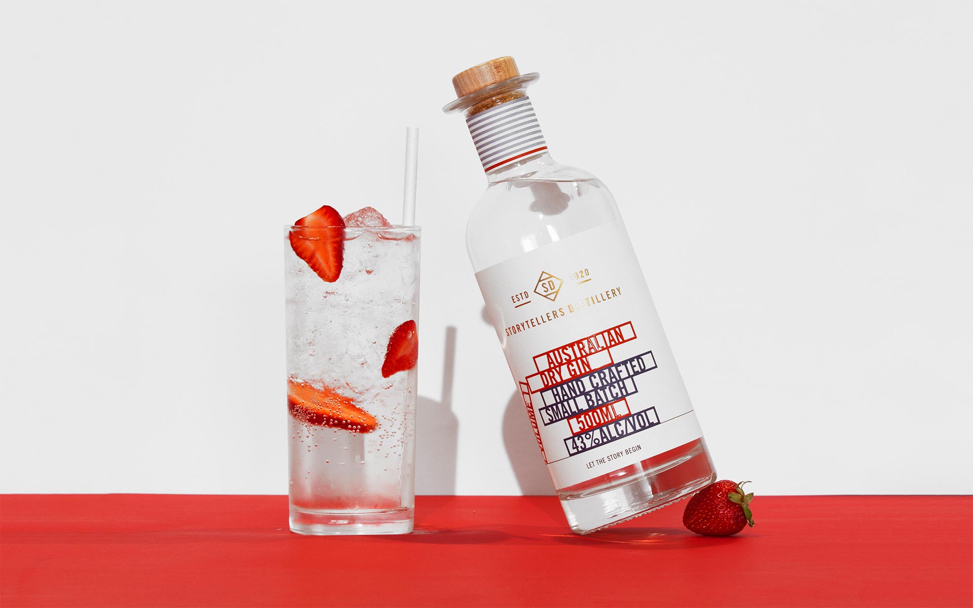 Storytellers Distillery volume 1 gin balancing on a strawberry along a gin and soda with freshly sliced strawberry
