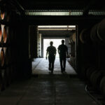 Two staff members silhouetted against an open doorway, existing the St Agnes Distillery barrel cellar