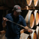 Worker sampling St Agnes spirit from the barrel